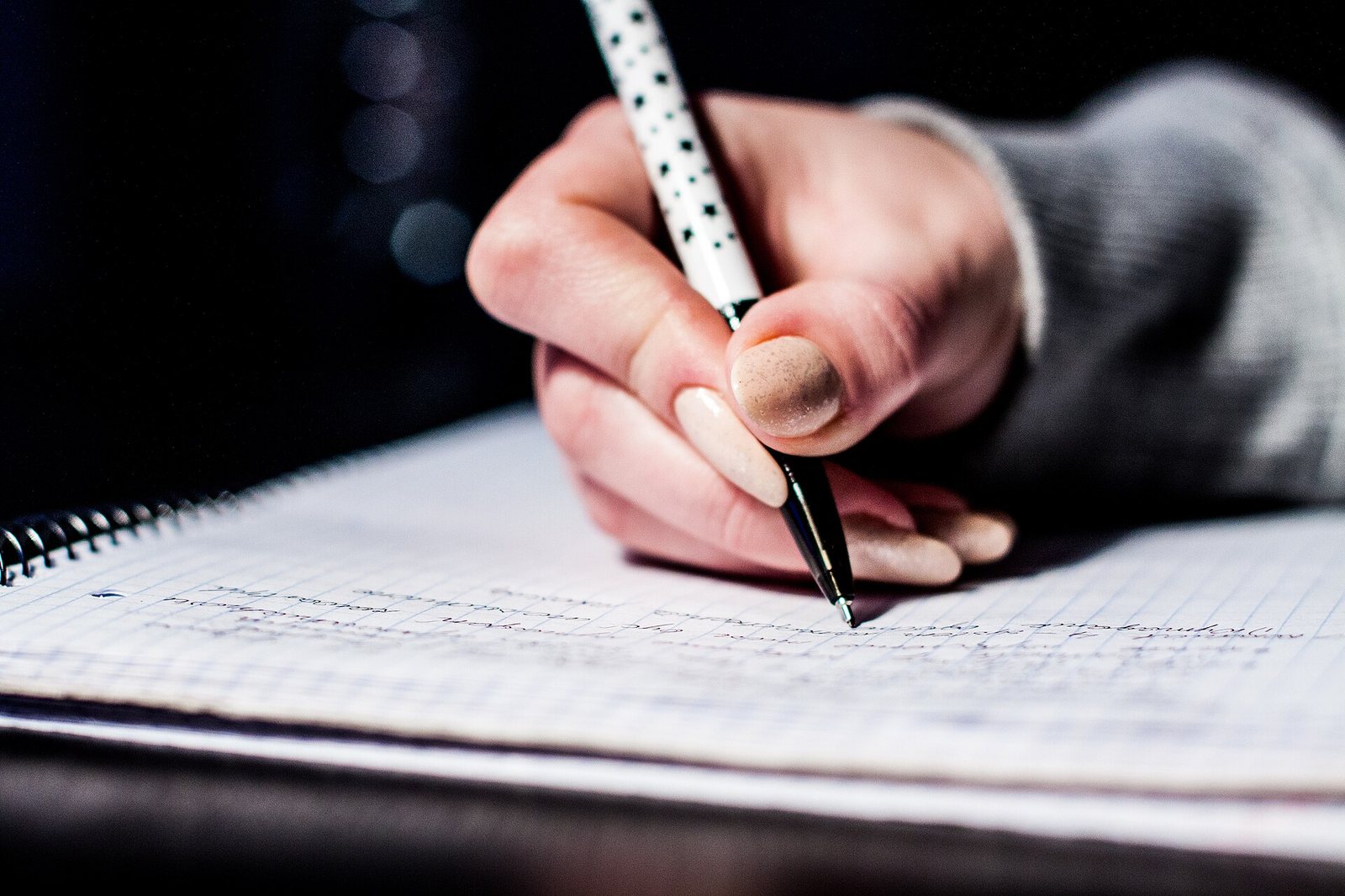 A hand writing in a notebook with a pen